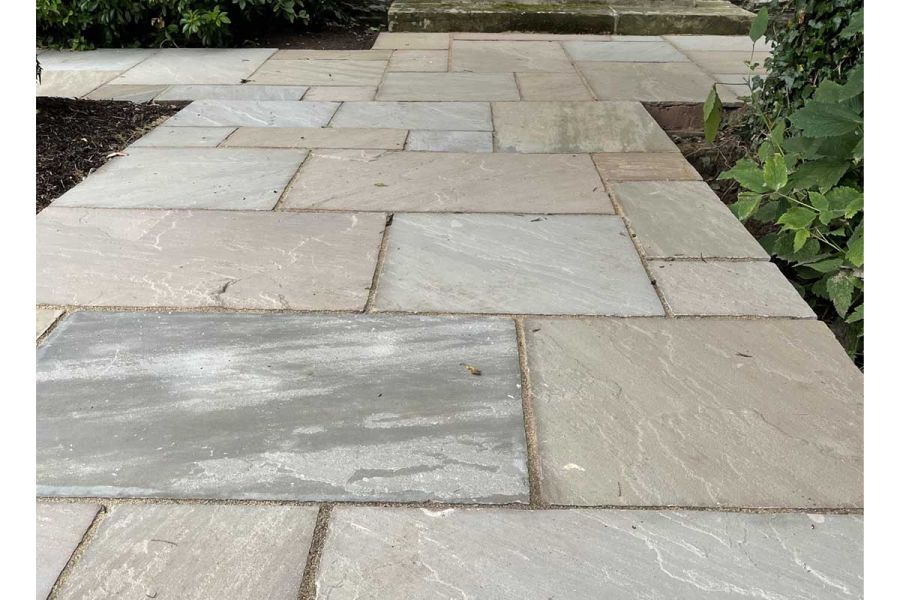 Wide path of Raj Green Indian sandstone project pack slabs meets matching path at right angles between planted beds.