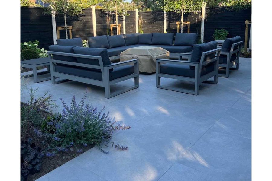 Large modular garden lounging set positioned around a covered firepit and sat on top of a large Polvere porcelain patio.