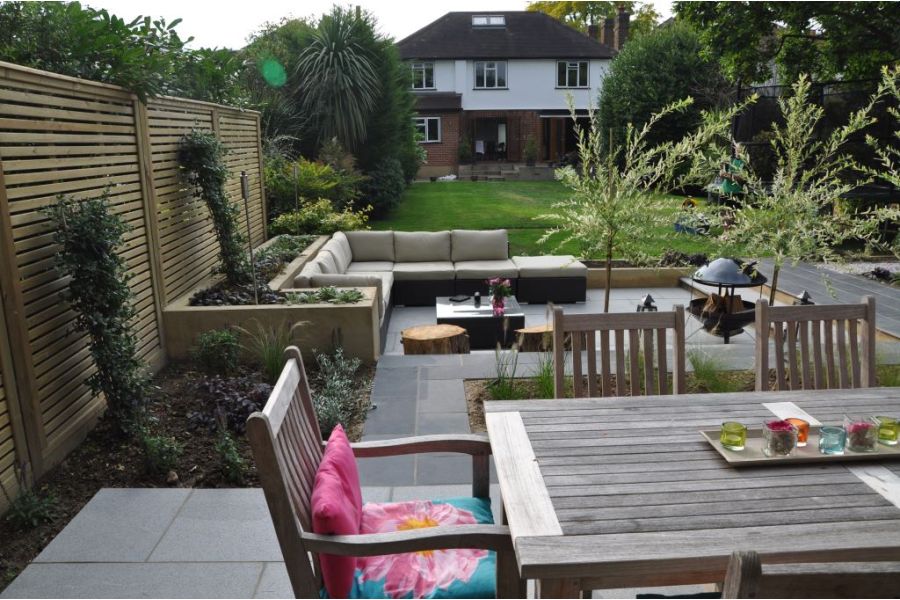 View to house from 3-level patio at bottom of garden, with dining set and large modular sofa on Midnight Black limestone paving.