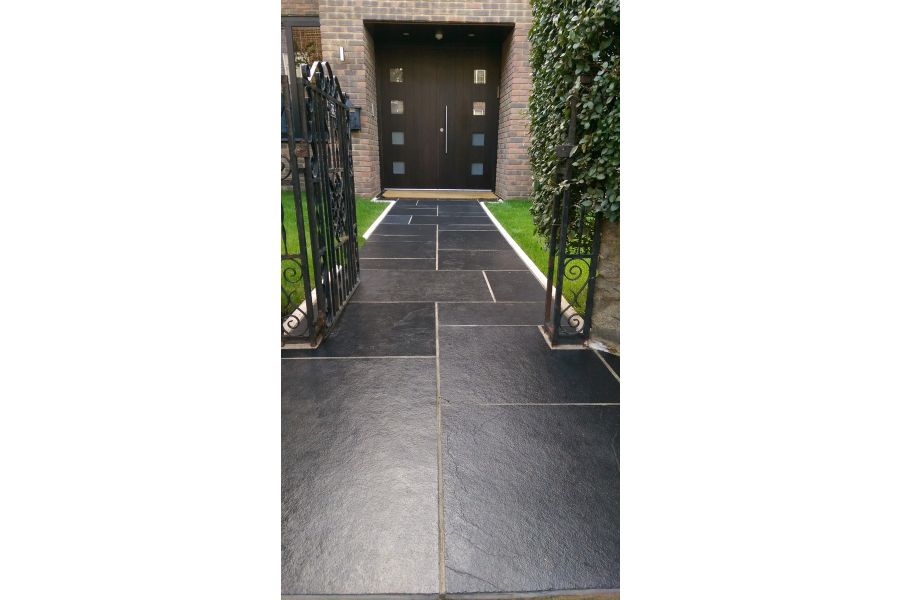 White-edged path of Midnight Black limestone slabs, treated with colour-enhancing sealant, leads to large front door.