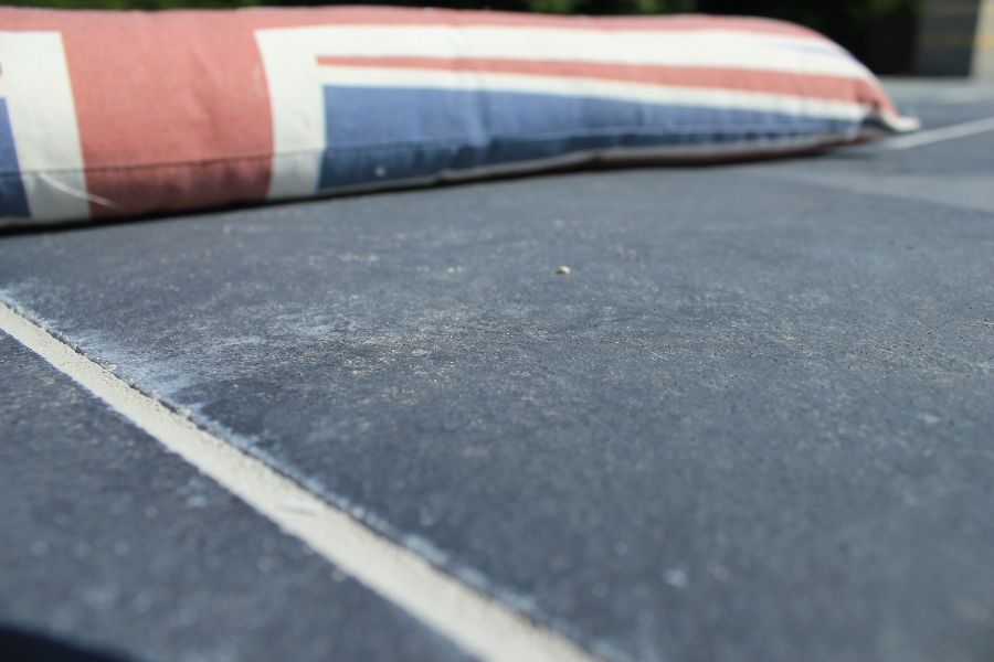 Ground-level view of Midnight Black limestone paving slab with white joints and Union Jack cushion in background.