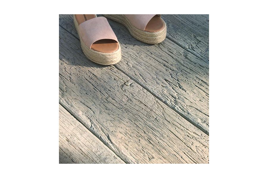 Close-up of Driftwood Millboard decking, showing realistic grain and antique look of planks. 2 espadrilles at top of picture.
