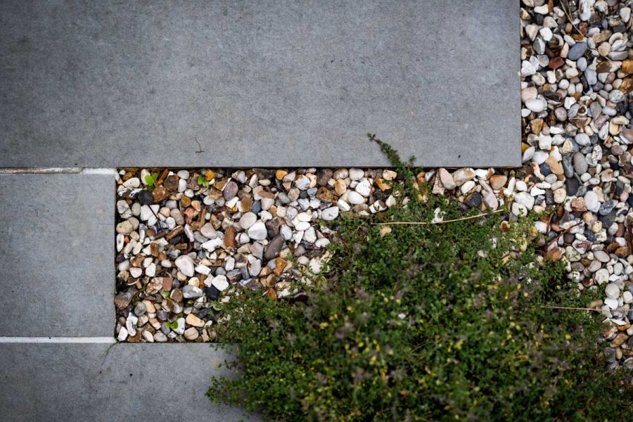 Looking directly down onto Steel Grey porcelain paving slabs with mixed gravels and heather planting overspilling.
