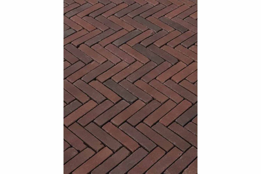 Close view of Novara Clay Brick Paving laid herringbone fashion unjointed, showing tumbled edges and varied tones of red and grey.
