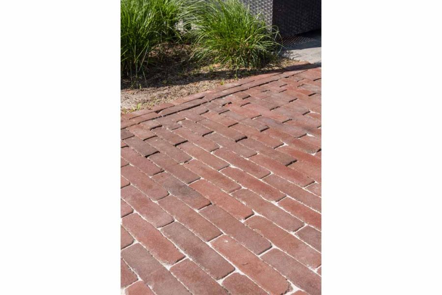 Close view of Novara clay pavers jointed with sand. 2 rows of matching brick paving edge paved area, dividing it from gravel.