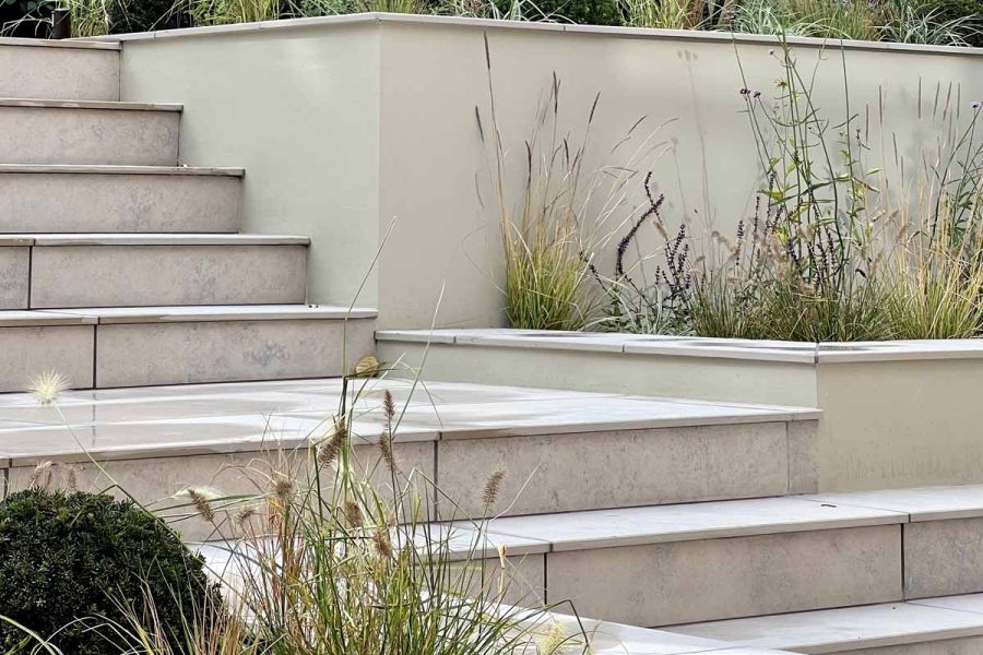 8 Jura grey porcelain garden steps, one very wide, with matching risers and all joints matching, rise past planted beds.