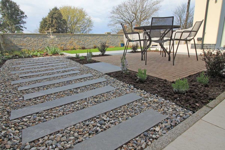 Steel Grey Porcelain Planks used as stepping stones from one end of the garden to the other, clay paved area hosts garden dining set.