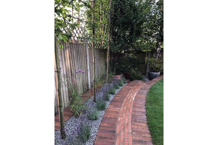 Soldier courses of Bromley Paving Bricks laid flat either side of on-edge pavers in running bond, in path by Outsiders Landscaping.