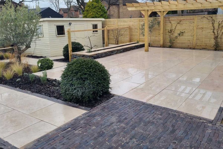 Mixed paving of grey Lugano Dutch clay pavers and beige limestone, with wooden pergola, narrow rectangular beds and a garden room.
