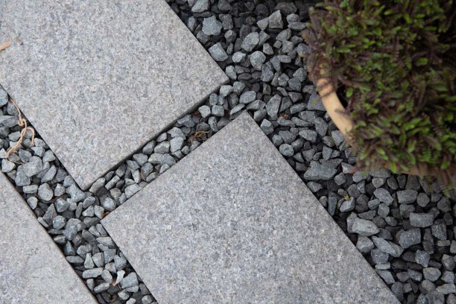 RHS Chelsea 2022, close-up view of Dark Grey Granite Plank Paving with matching gravel adorns the Pots and Pithoi stand.