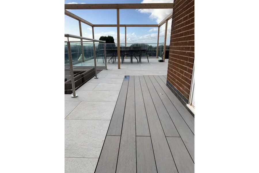 Pebble Grey Brushed garden decking and Ancient Porcelain Paving on terrace with railings and furniture. Design by Creative Roots.