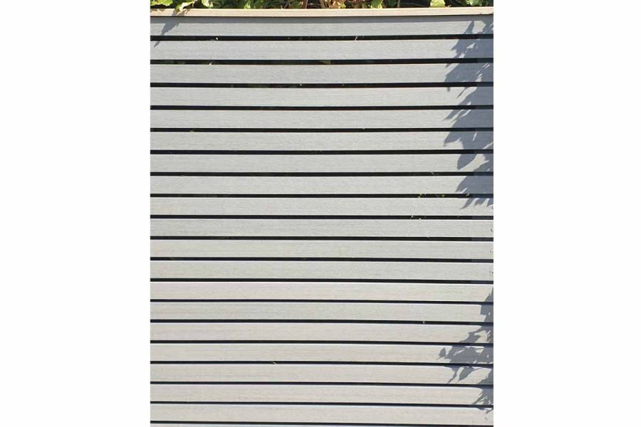 Close view of Pebble Grey Composite Battens attached as horizontal slats to garden screen framed in contrasting colour in brown.