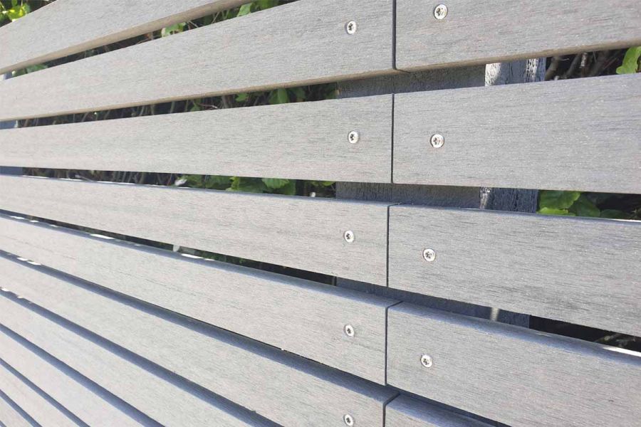 Close-up, oblique view of Pebble Grey Composite Battens, showing screw-heads at ends of neatly joined slats in long garden screen.