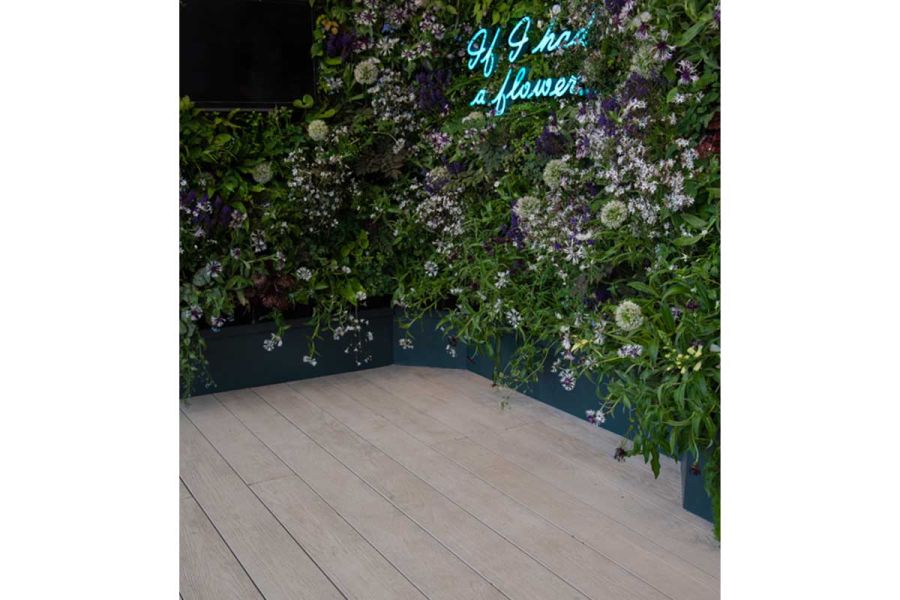 Living wall with “If I had a flower” written in fluorescent lighting edges empty corner laid with Limed Oak Millboard Decking.