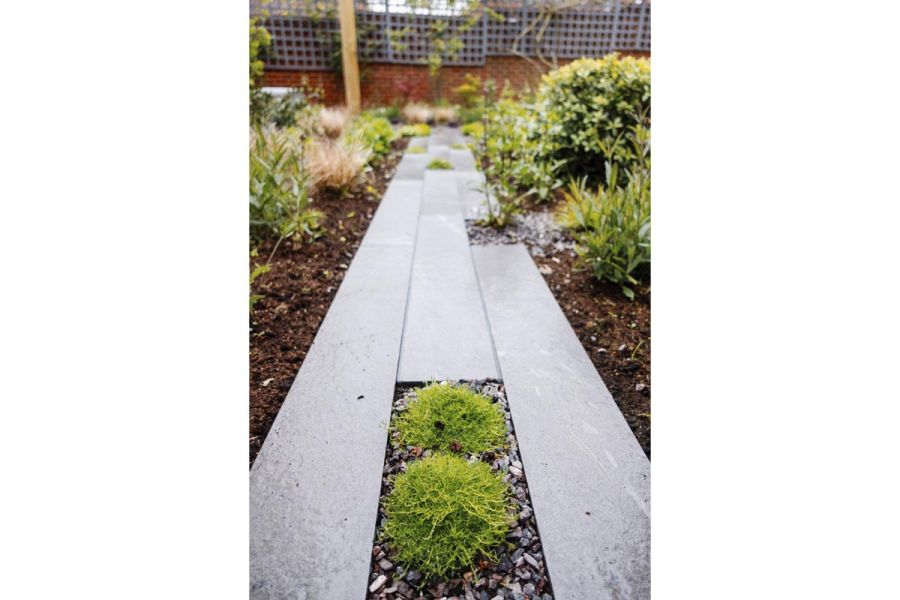 A detailed shot of Platinum Grey Porcelain Planks, showing their appealing texture, adorned with moss and gravel in between.