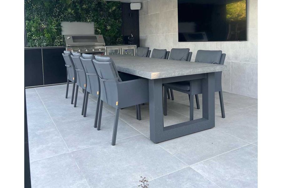 Covered outdoor kitchen area with barbecue, large dining table and the floor and walls surfaced with Polvere 800x800 porcelain pavers.
