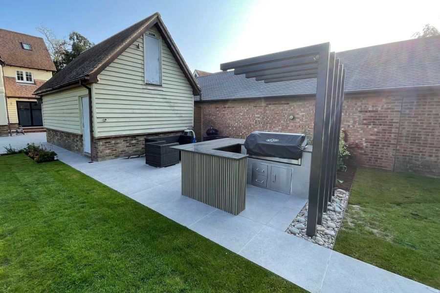 Contemporary barbecue area with wicker garden furniture and surrounded by a light coloured porcelain patio.