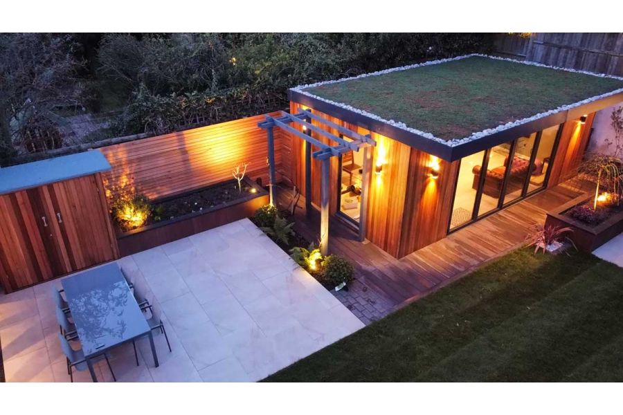 Elevated view of a rear garden featuring, office building, porcelain patio, raised flower beds and cedar screening.