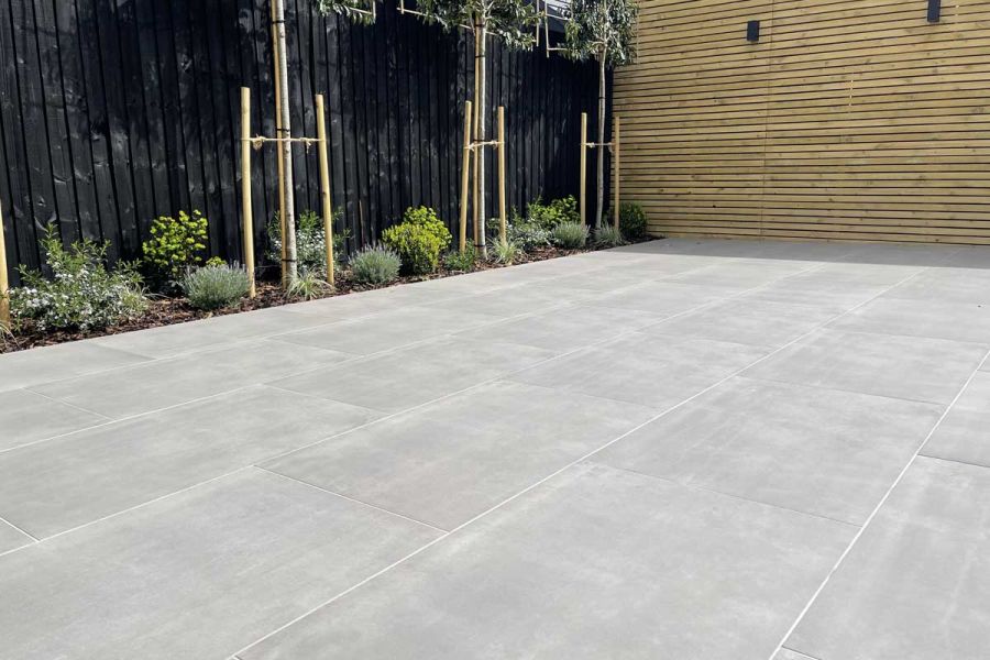 Large Polished Concrete porcelain patio set against a planted flower bed, painted fence panels and bespoke timber screens.