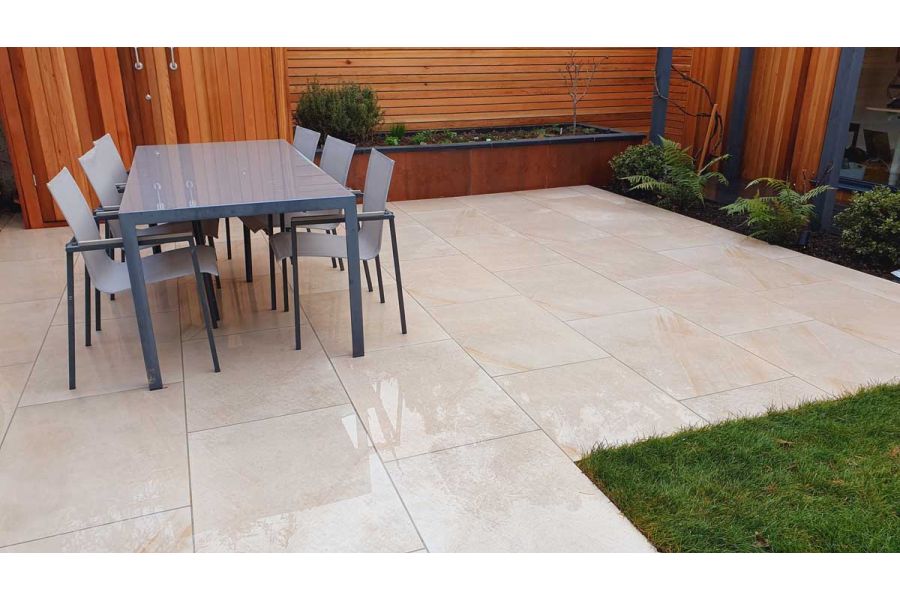 Wet light coloured porcelain patio with a rectangle six seater dining set against a back drop of cedar screen and matching storage unit.