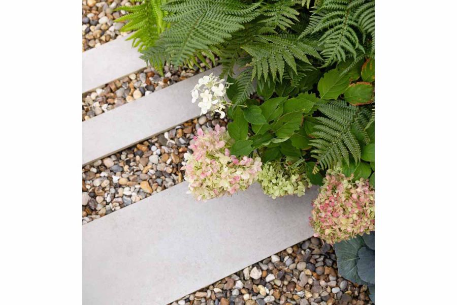3 strips of florence grey porcelain have pebbles laid in between, with green and pink plants spilling out from the flowerbeds.