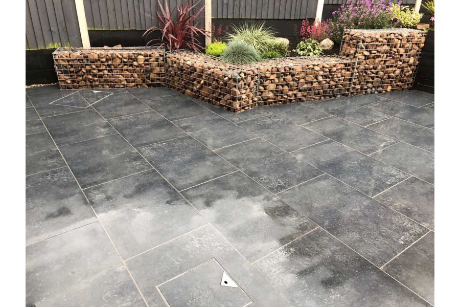 Charcoal porcelain patio with raised planters constructed from gabion cages filled with large river washed pebbles.