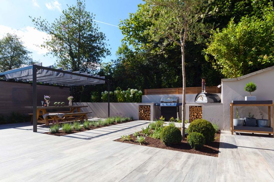 Large courtyard garden with a Cinder porcelain patio, low level flower beds and a large covered dining area.
