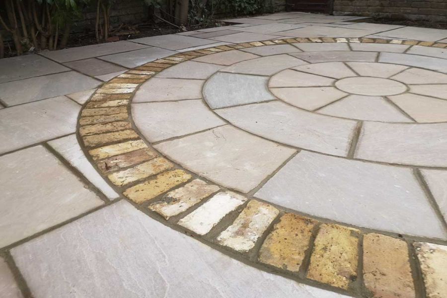 Raj Green India Sandstone slabs, surrounding matching paving circle outlined in setts. Design by Steve Hooper Landscapes.