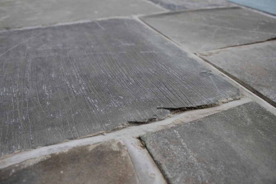 Close-up of reclaimed Yorkstone paving slabs with wide joints, showing markings, colours and surface texture.