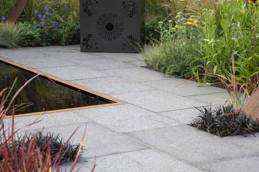 Dark Grey Granite paving with Corten steel edged pond, metal cube seat and grassy planting. Design by Charlie Bloom, Hampton Court.