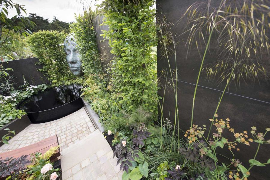 Show garden with large verdigris face, curved pond and wall faced with Steel Dark Designclad external porcelain cladding.