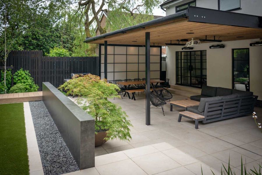 Japanese style patio paved with Slab Khaki porcelain outdoor tiles. Seating under pergola and potted Acer. Design by Robert Hughes.