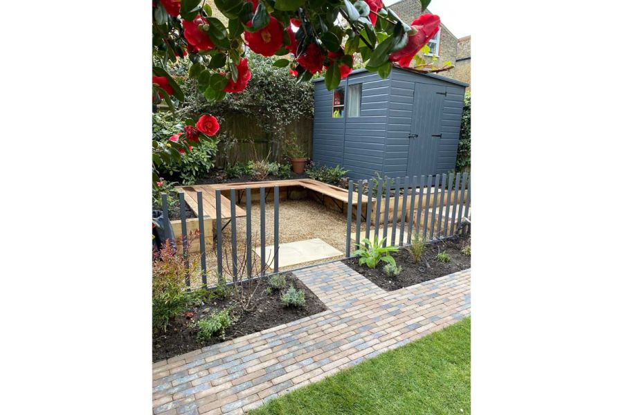 Clay paver path leads to area with gravel and Harvest Sandstone Paving slabs, bench and shed. Design by Robert Jackson Gardens.