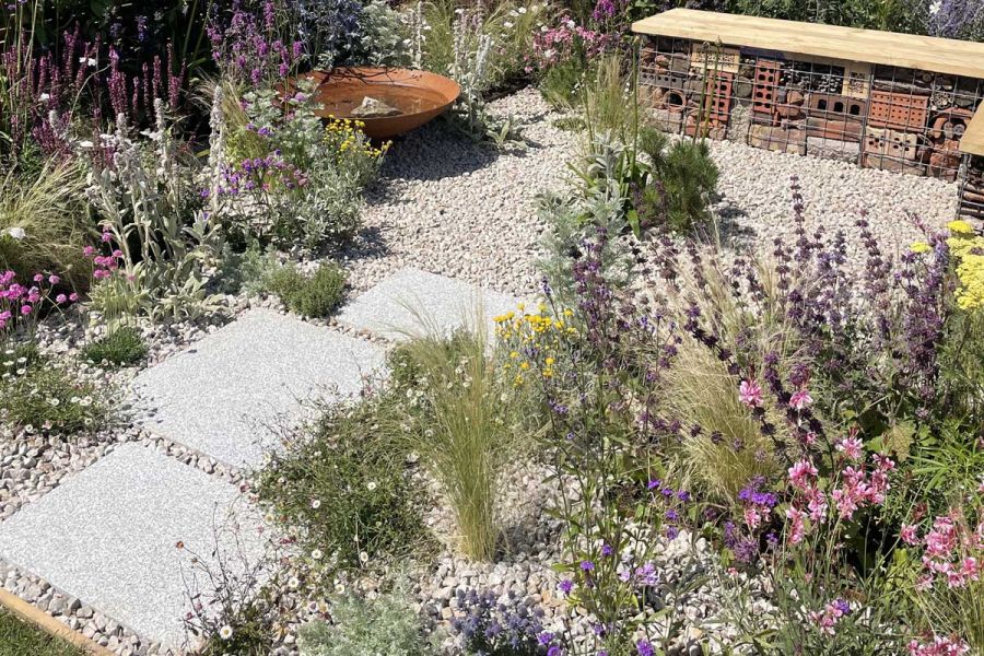 3 Silver Grey Granite slabs in gravel of dry garden with bug hotel bench of gabions and planks. Design by Tone and Manner.