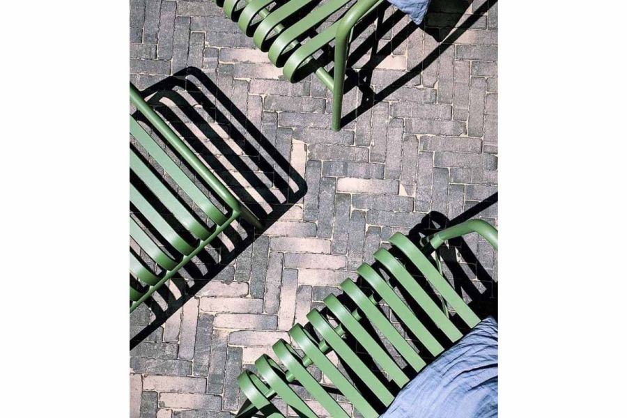 Close view from above of Silver Grey Multi clay pavers, laid herringbone pattern, with green metal furniture casting shadows.