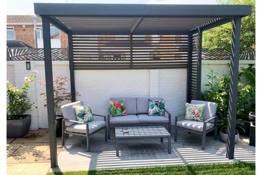 Pebble Grey Composite Battens provide garden screening at top of boundary wall, affixed to pergola that covers seating area.