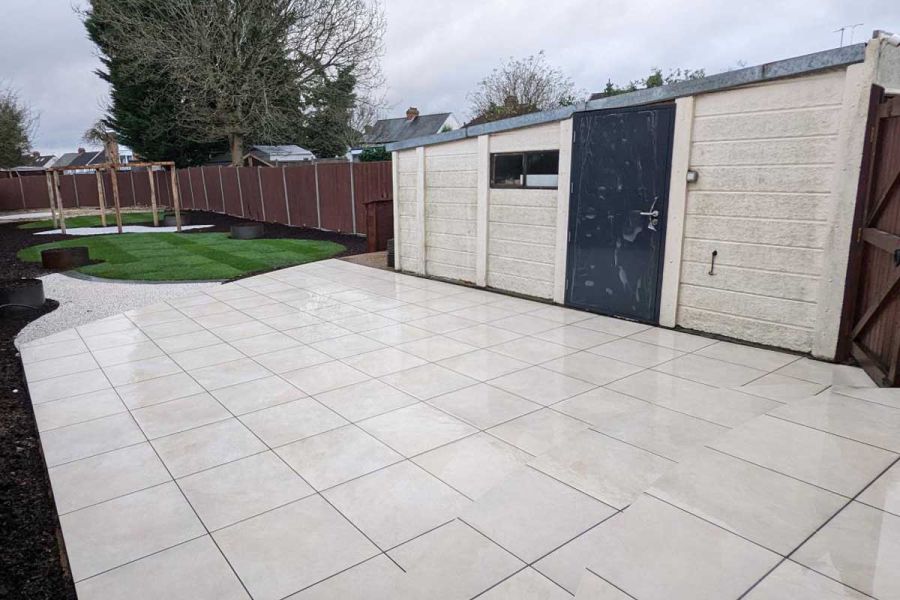 Slab Khaki Porcelain used as paving and steps next to white shed. Pergola in background on lawn area.