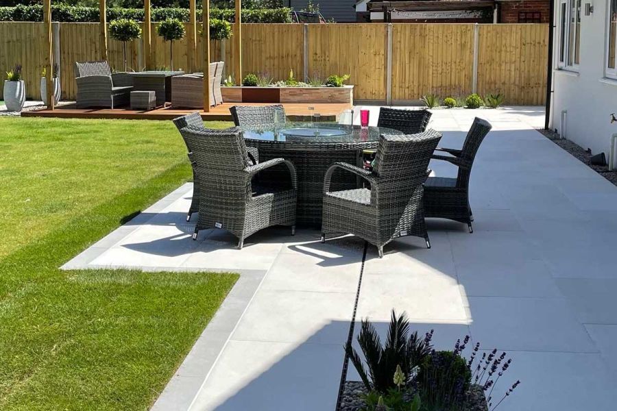 Rattan dining set on Florence Grey Porcelain patio with slot drain and dark edging. Built by Smith and Gorman Groundwork.