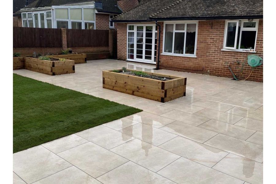 Large Ash Beige porcelain patio coming off the back of a bungalow with a number of large raised timber planting beds set into the paving.