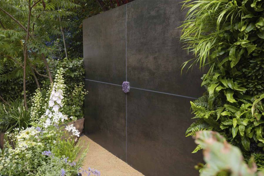 Rectangular wall faced with 4 Steel Dark DesignClad panels with mauve grouting meeting at central roundel.