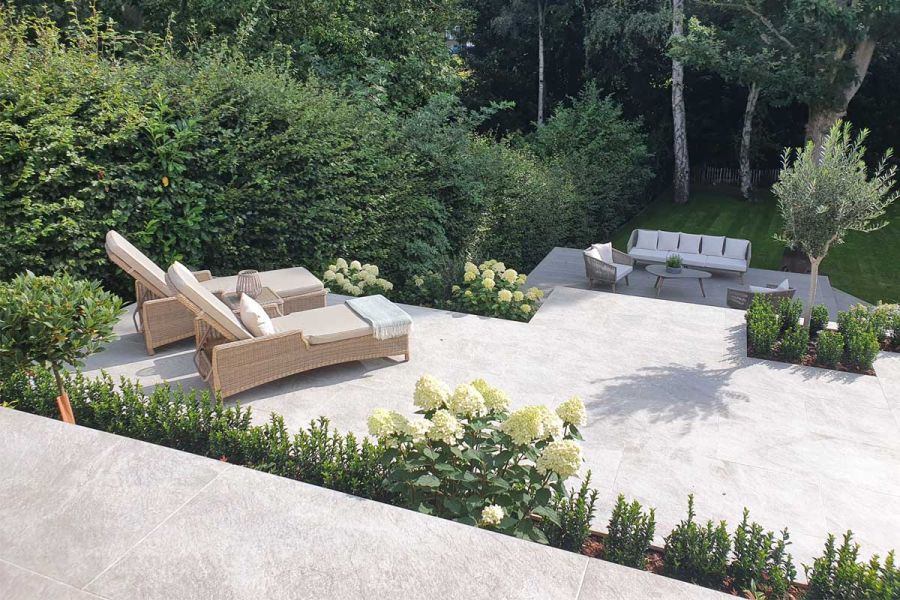 2 rattan sunloungers on Steel Grey Porcelain Paving terrace with beds with hedge and hydrangeas. By Landscape Design Studio.