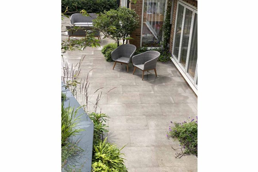 Wet Steel Grey porcelain patio leading off bi-fold patio doors with 2 matching wicker garden chairs.