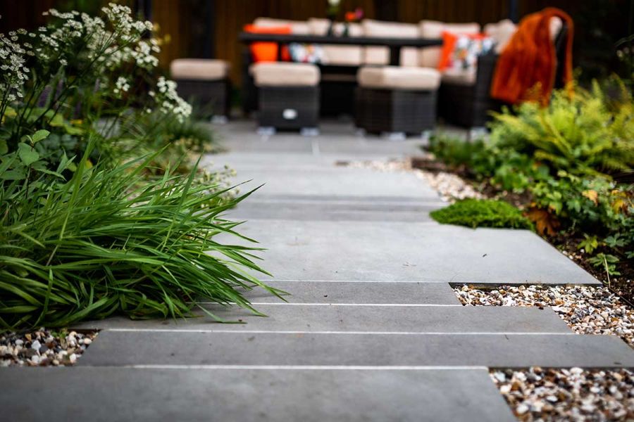 Steel Grey porcelain paving slabs cut down to various sizes to form a path towards an outdoor dining area.