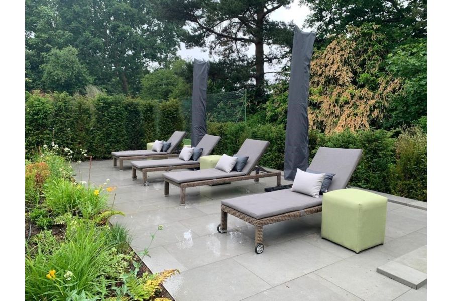 Steel Grey porcelain patio with 4 sun loungers, parasols and surrounded on all sides by established shrubs and hedging.