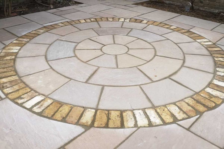 Raj Green Indian Sandstone patio pack slabs surround paving circle in matching stone, delineated with setts. Built by Steve Hooper.