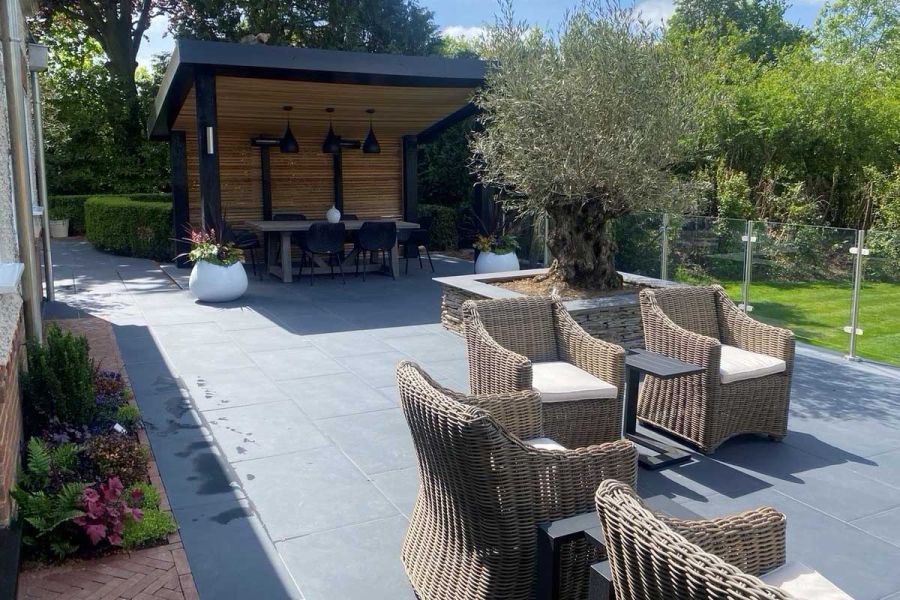Florence dark porcelain patio with covered dining area, 6 rattan armchairs and wood burner. Design by Thames Valley Landscapes.