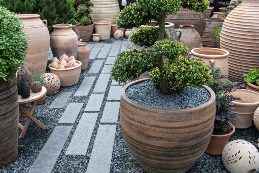 Dark Grey Granite linear slabs laid in gravel between large collection of variously sized pots on RHS Chelsea trade stand 2022.