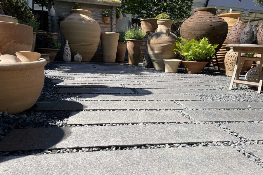 Close view of Dark Grey Granite Plank Paving with matching gravel infill between slabs on Pots and Pithoi stand, RHS Chelsea 2022.