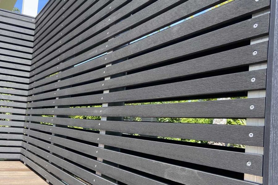 Tall screen of Dark Ash composite battens seen from one end, screws neatly placed at midpoint of width. Free UK delivery available.