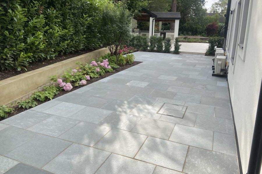 Side area of house paved with Kota Blue Limestone. Long, narrow angled border edges a raised bed. Design by Thouvenin Landscapes.